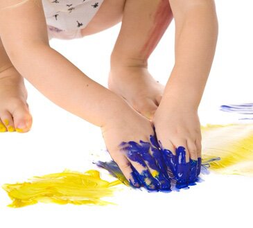 closeup of child painting hands dirty in blue color over white